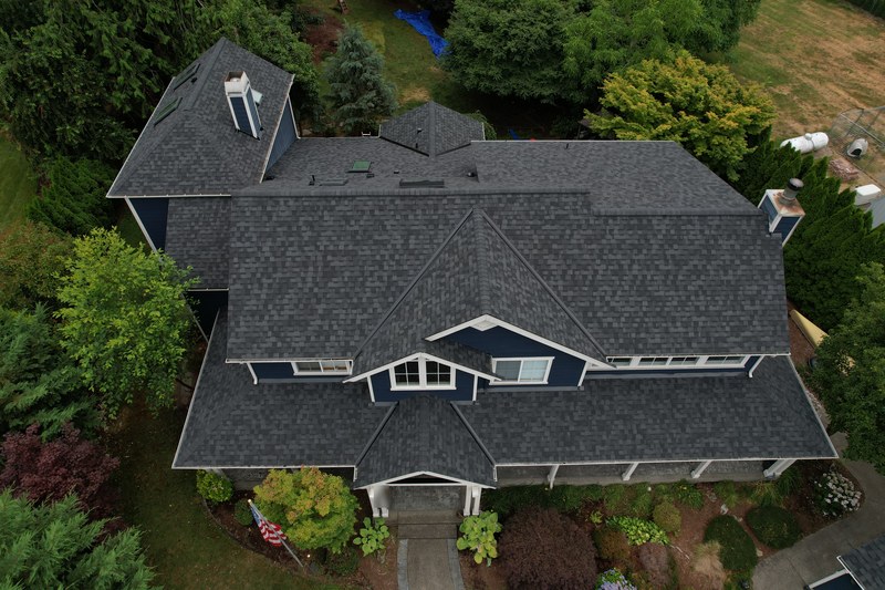Two story navy blue house with a new charcoal asphalt shingle roof installed by Titan Roofing, seen from above